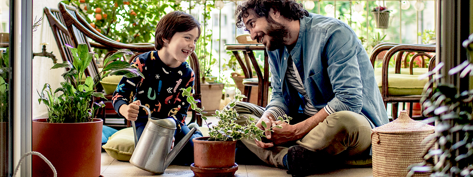 Father and son watering plants on their terrace.