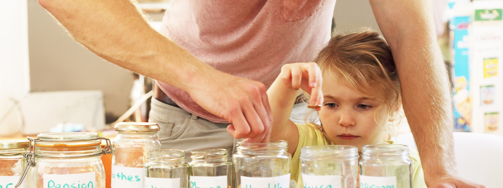 Young girl and father putting money into savings jars.