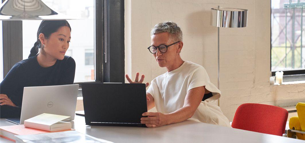 Two people brainstorming at a desk with laptops.