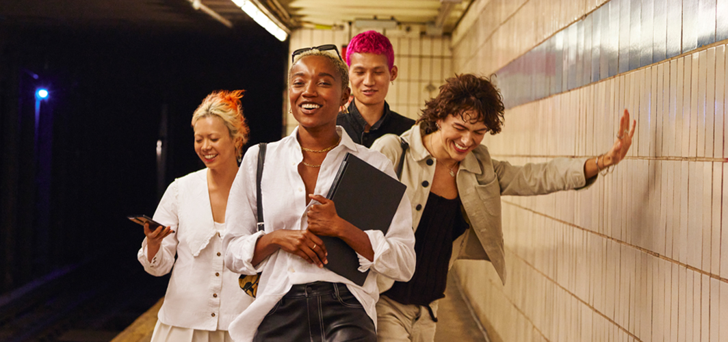 A small group of people laughing and smiling in the subway station.