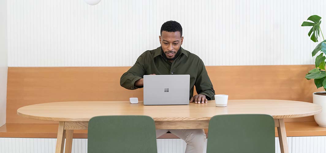 A man at a coffee table using a touch screen laptop.