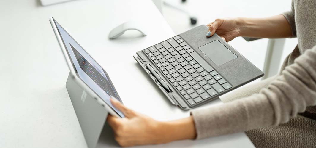 A person preparing to connect a small keyboard to a tablet.