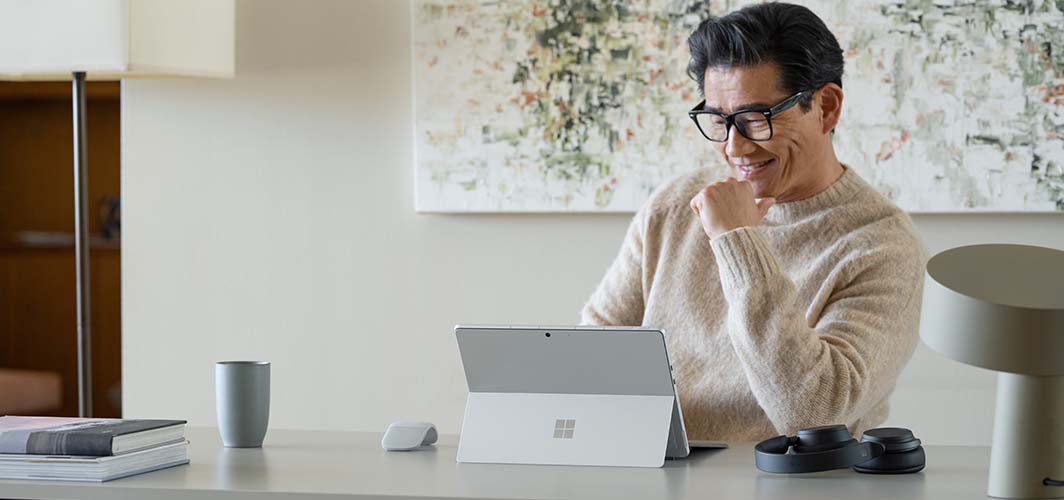 A man sitting at a conference table smiling at a laptop screen.