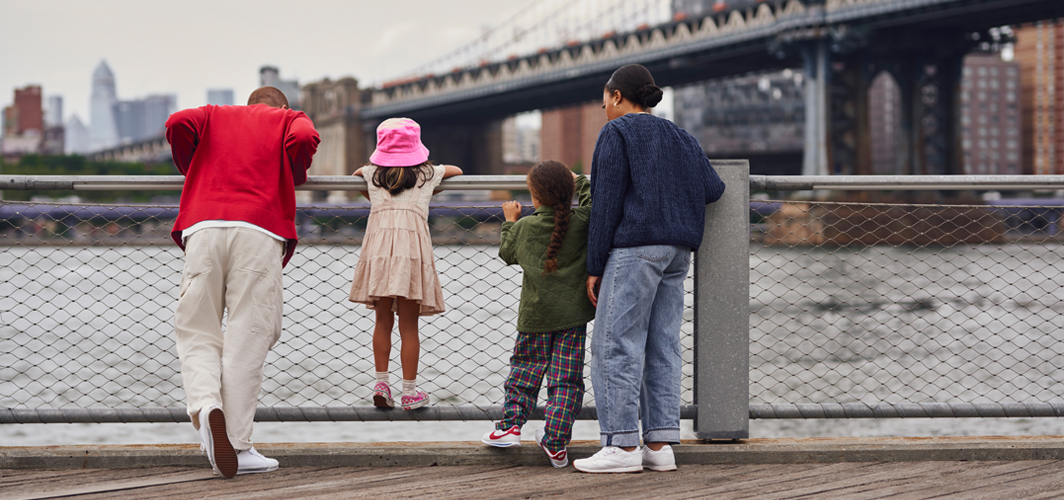 A family standing at a fence next to a river.