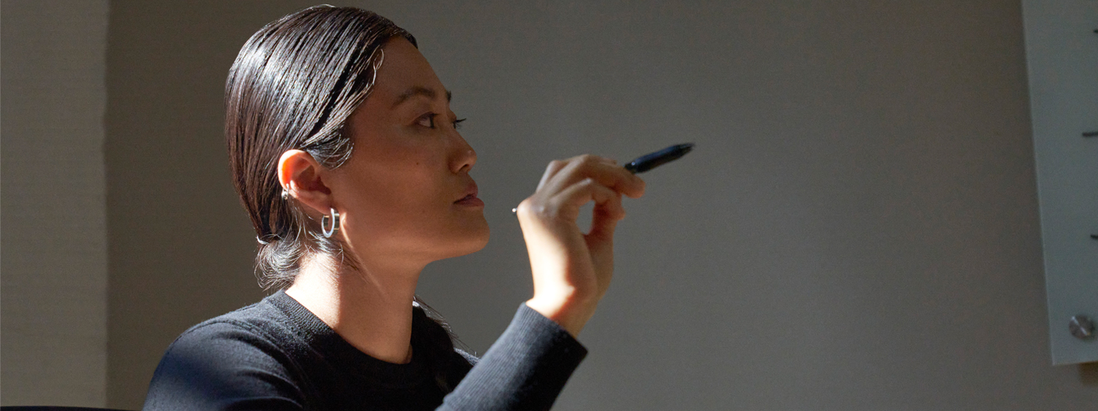 Woman gesturing with a pen.