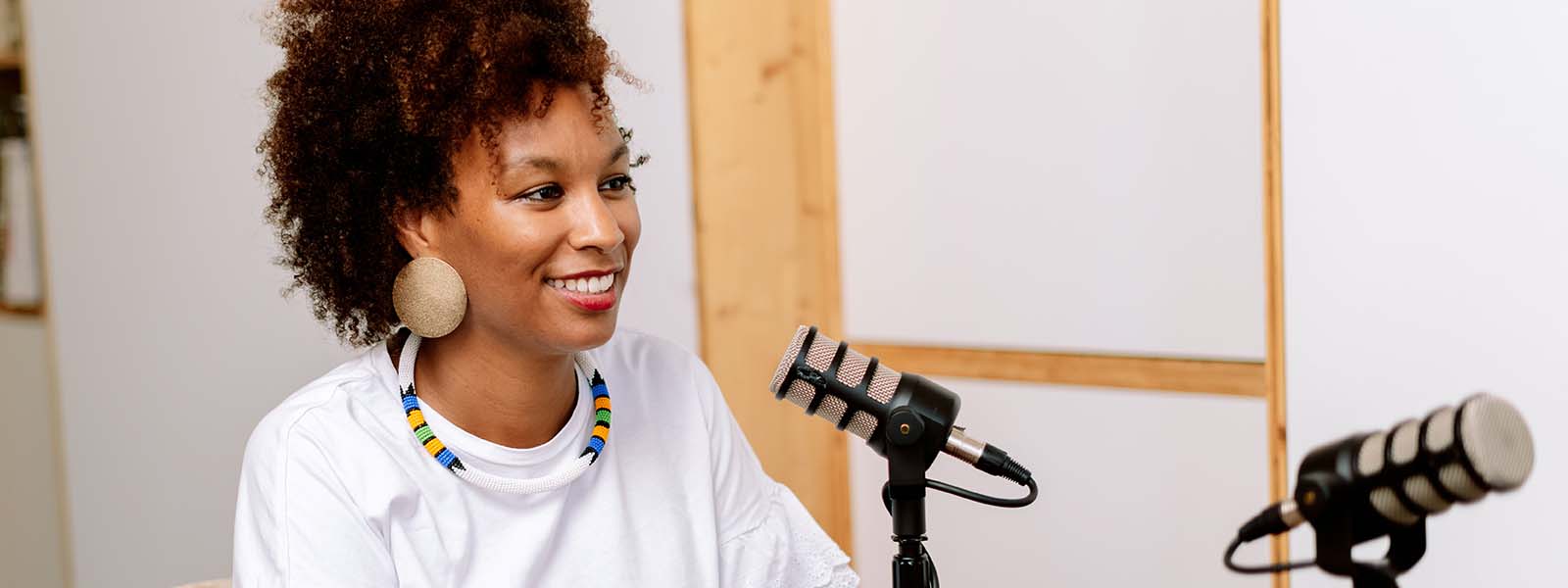 A woman smiling while speaking into a microphone at a table.