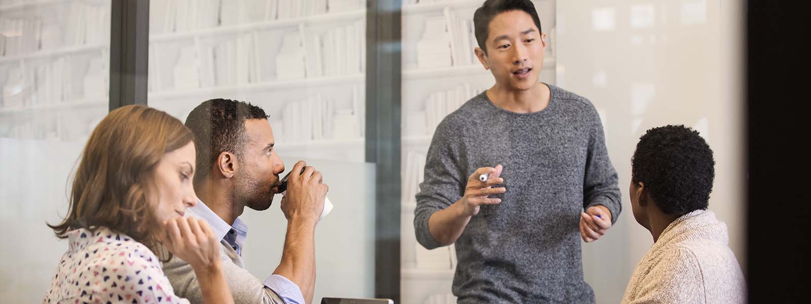 A man standing in front of co-workers presenting an idea.