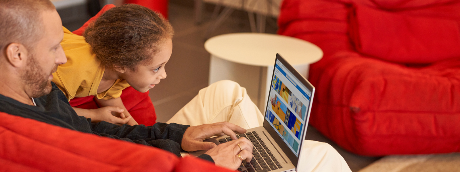 A man and a young child looking at art on a laptop.