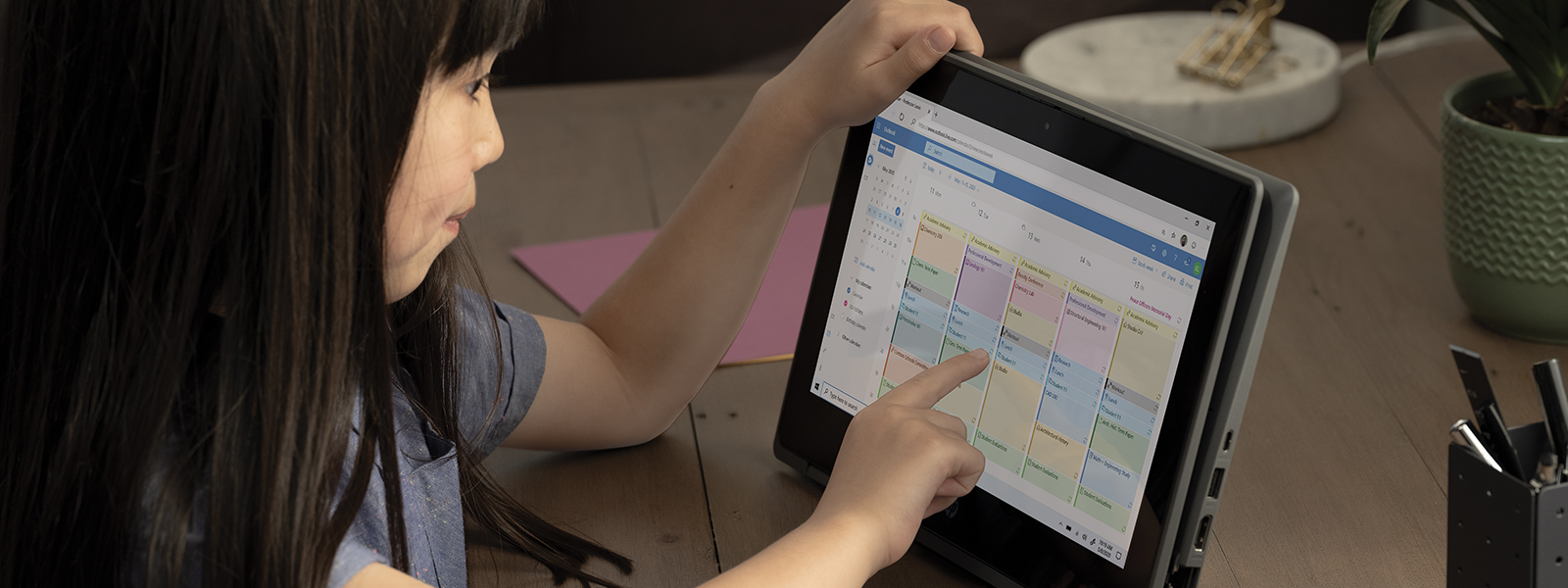 a little girl looking at the outlook calendar on a tablet.