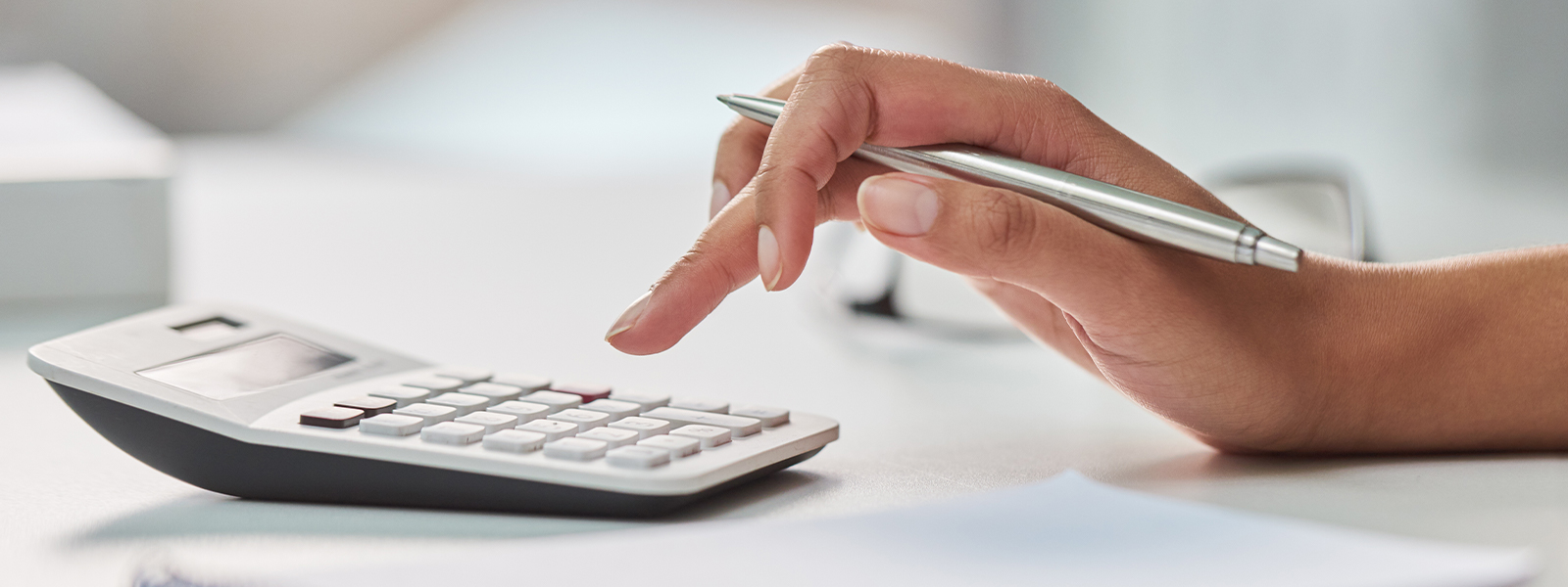 A woman working out her finances with a calculator and a notepad in her office.