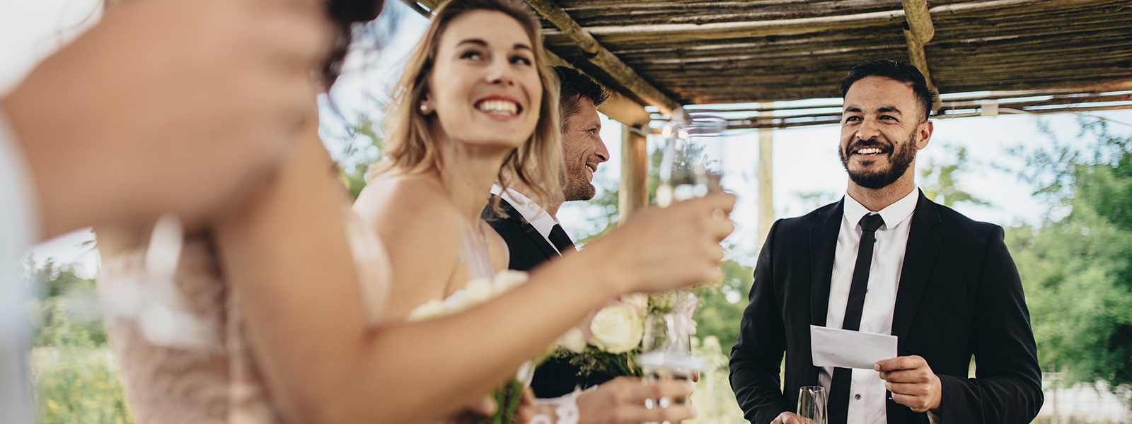 A man in a tuxedo giving a wedding speech to a wedding ceremony.