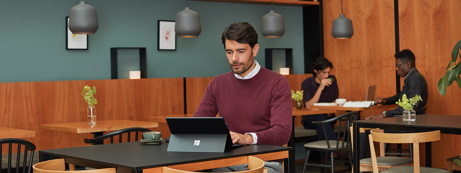 a man inside café working independently on Surface Pro 6. 