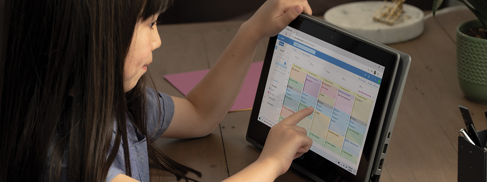 A school age girl opening an appointment on Outlook Web App on an HP Probook x360 in the home office. 