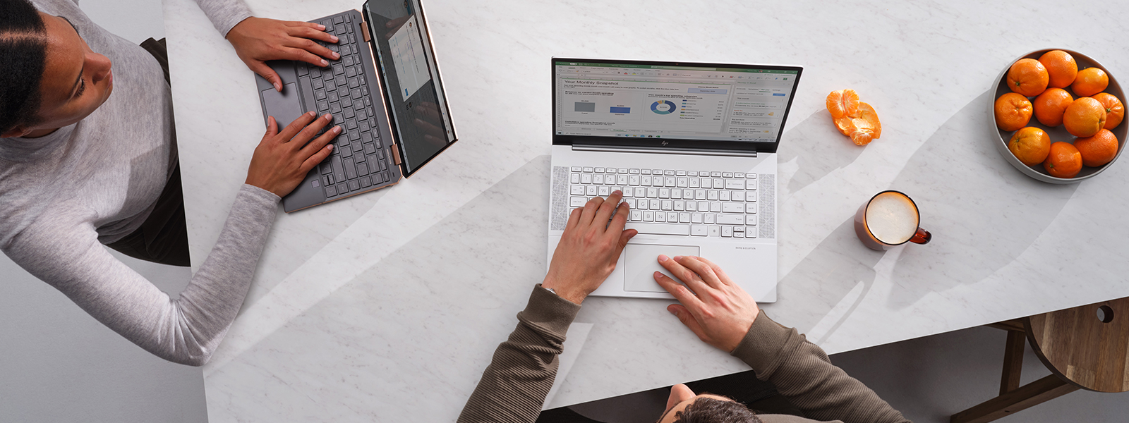 two people working from home on a kitchen counter while using laptop.