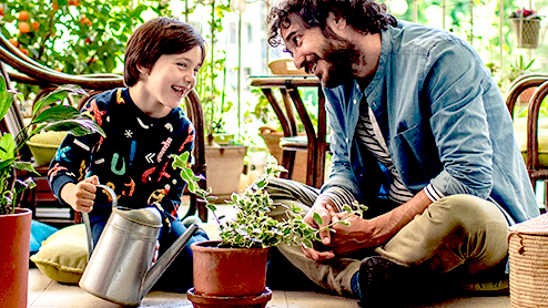 Father and son watering plants on their terrace