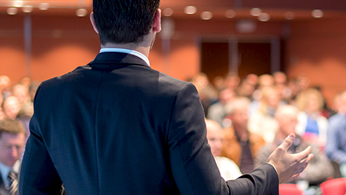 a man giving a presentation in front of a large crowd.