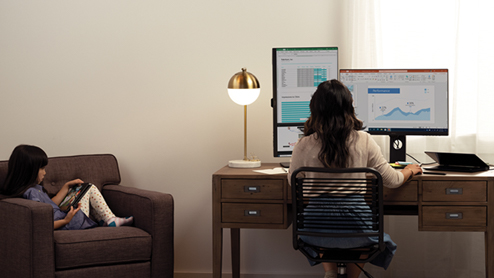 A mother and her daughter are working and learning remotely in their living room. Mother is working on PowerBI dashboard.