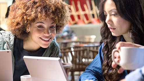 Two girls looking at their laptop and smiling.