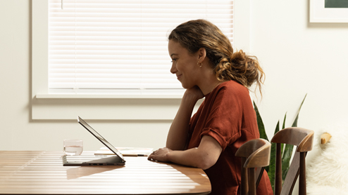 a woman working on dining room table with a Lenovo ThinkPad X1