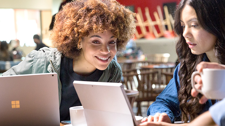 Two girls looking at their laptop and smiling.